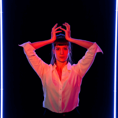 A woman holding her hands above her head, standing in a red light.