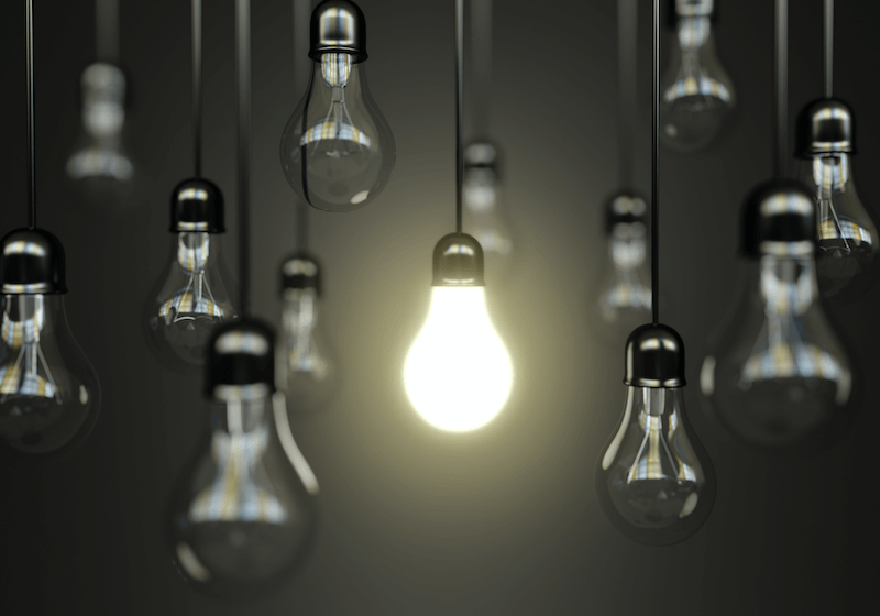 An image of hanging light bulbs, the central one is the only one turned on.