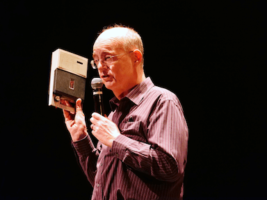 A man holding a tape recorder and microphone, looking away from the camera.