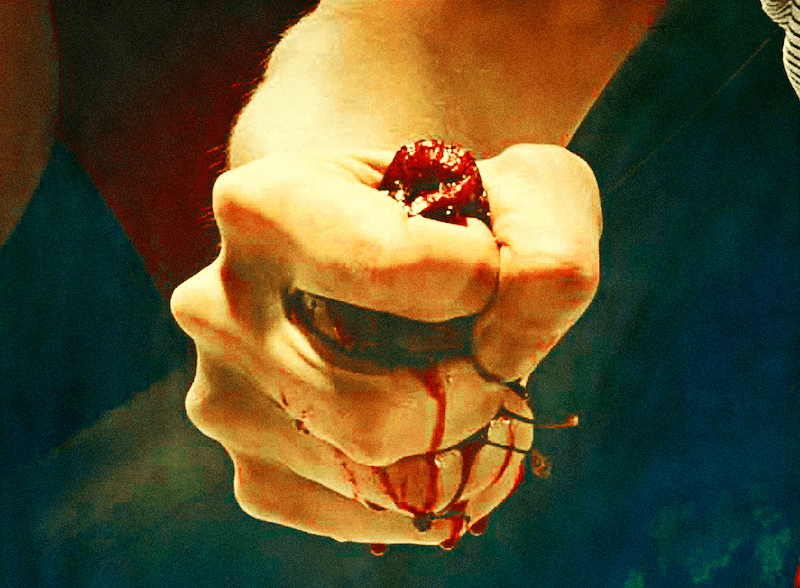 An image of a hand squeezing something, with blood trickling down.