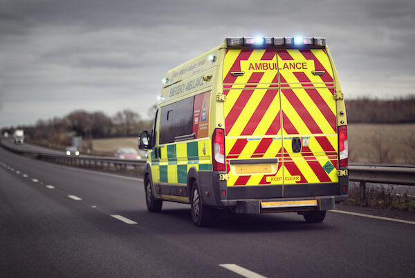 An image of the back of an ambulance driving on a motorway, with its lights flashing.