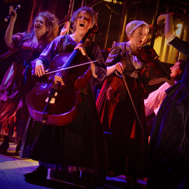 Three women cheering and playing instruments.