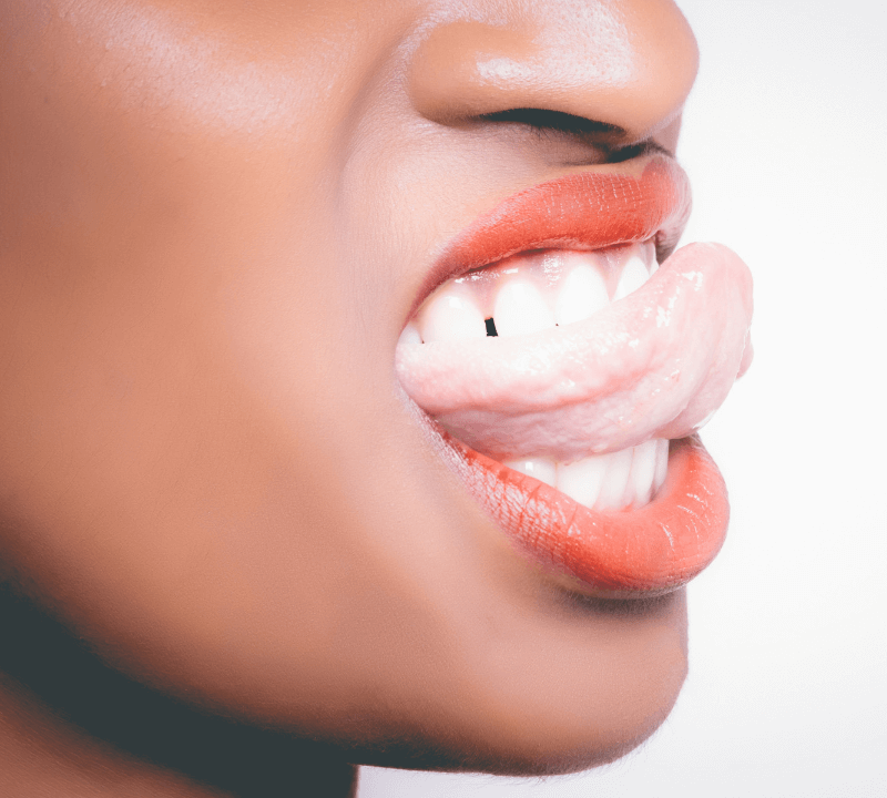 A close up of a woman biting her tongue in between her teeth.