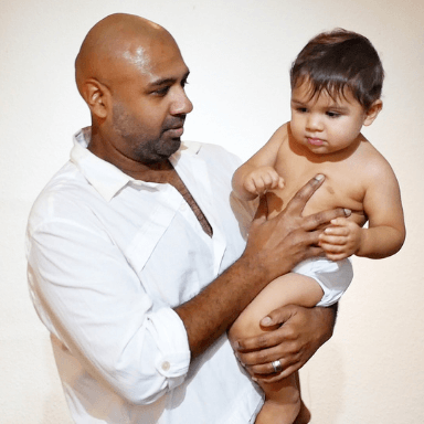 A man wearing a white shirt holding a baby.
