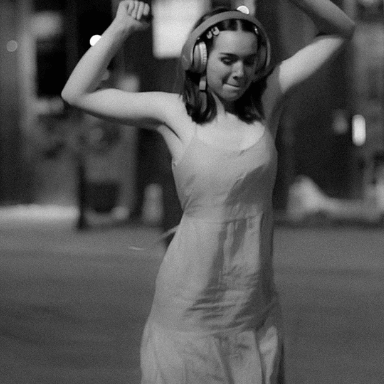 A young girl dancing in the street with headphones on.