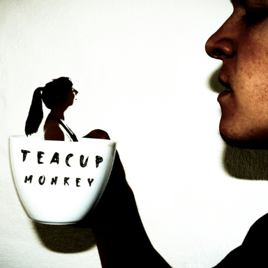 A shadow image of a girl in teacup, being held up by a hand.