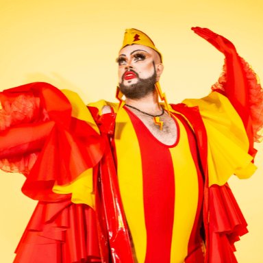 A person dressed up in drag, posing in a bright red and yellow striped outfit.