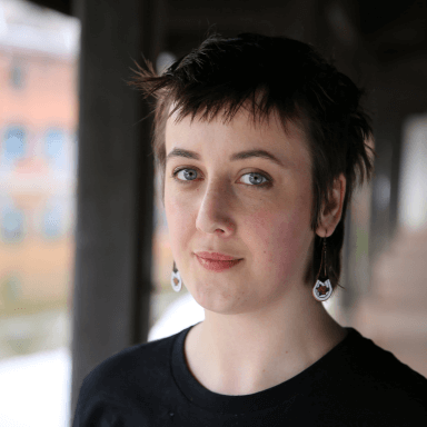 A person looking directly towards the camera, against a blurred background.