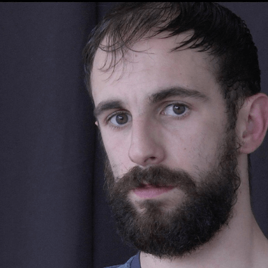 A bearded man looks directly at the camera