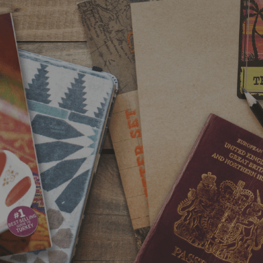 A passport, notebooks and magazines laid out and overlapping on a table.