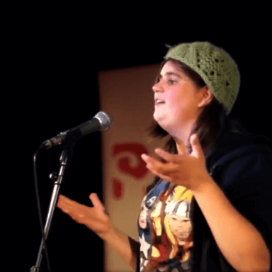 A person performing in front of a microphone, not looking towards the camera.