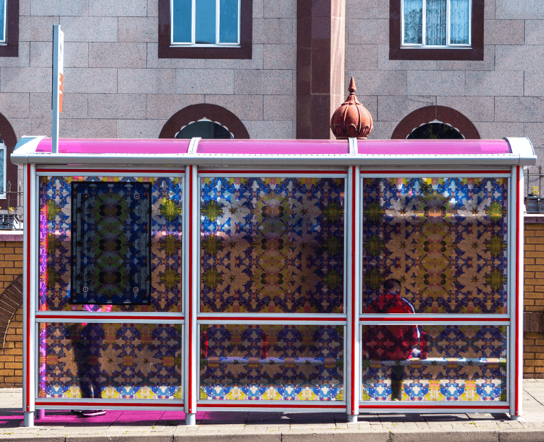 Photograph of a bus stop outside a temple, decorated with stain glass style patterns.