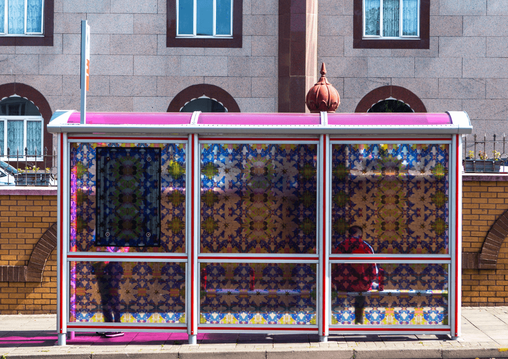 Photograph of a bus stop outside a temple, decorated with stain glass style patterns.