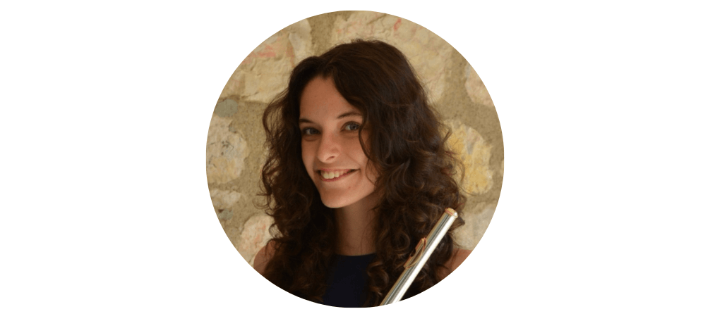 A woman looking directly at the camera smiling. She has long curly brown hair.